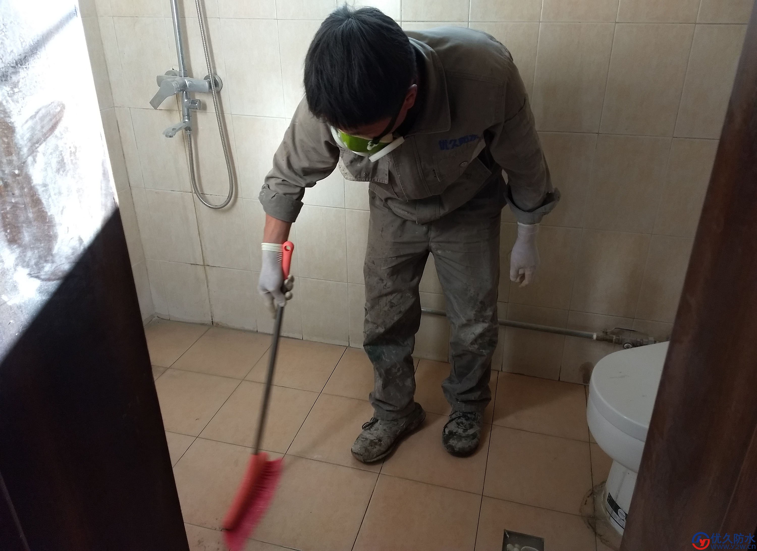 优久防水该工人正在用扫把扫动免敲砖防水材料